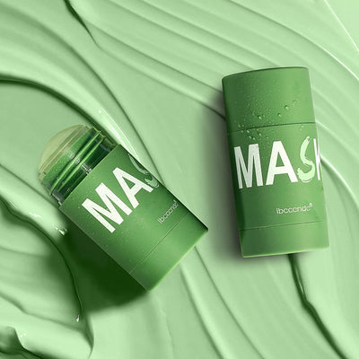 Green tea cleansing stick mask in a green cylindrical container with a removable lid, placed on a large green leaf, emphasizing deep cleansing skincare