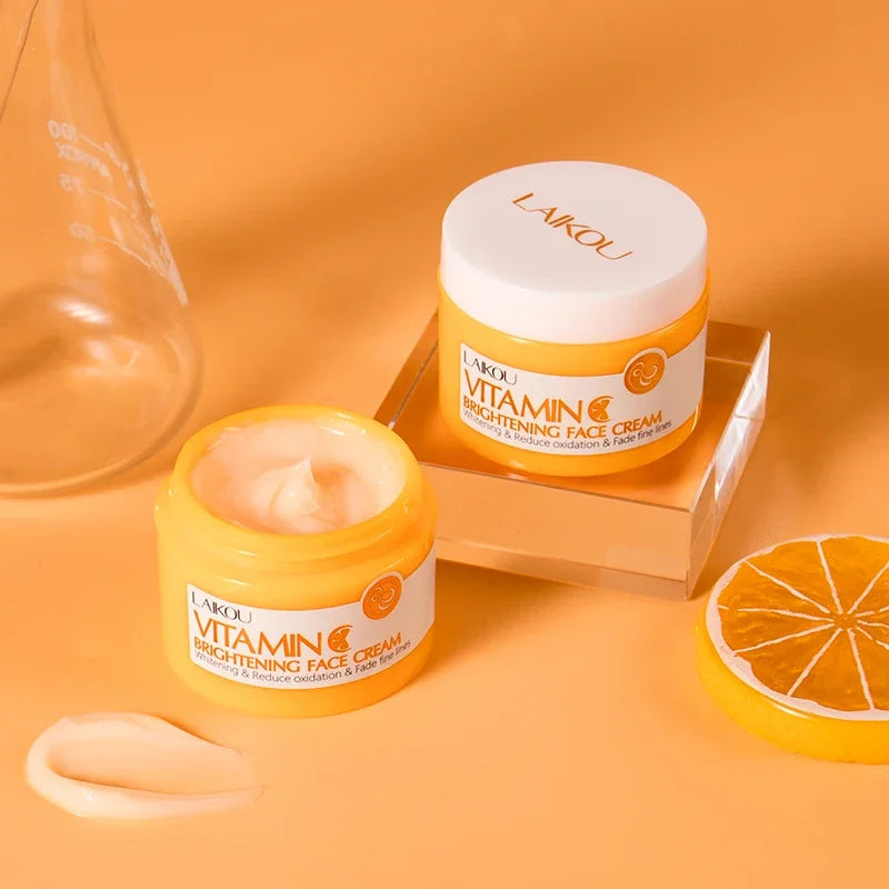 Yellow jar of LAIKOU Vitamin C Brightening Face Cream with white lid, creamy texture visible, placed on peach-colored background with glass beaker
